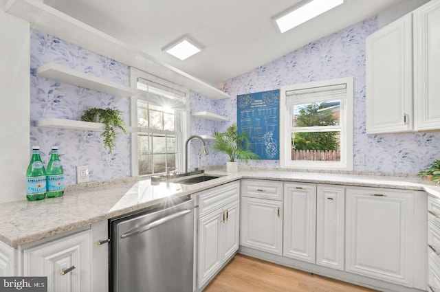 kitchen with light hardwood / wood-style floors, white cabinetry, sink, dishwasher, and vaulted ceiling