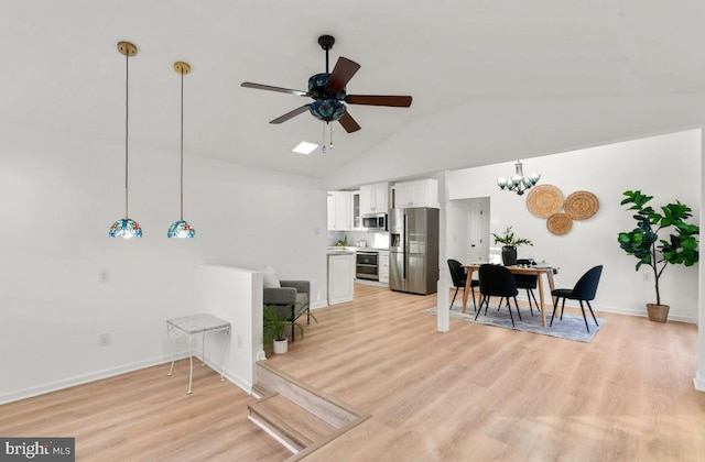 interior space with vaulted ceiling, light hardwood / wood-style floors, and ceiling fan with notable chandelier