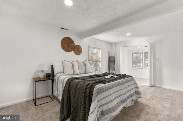 carpeted bedroom with multiple windows, a textured ceiling, and beam ceiling