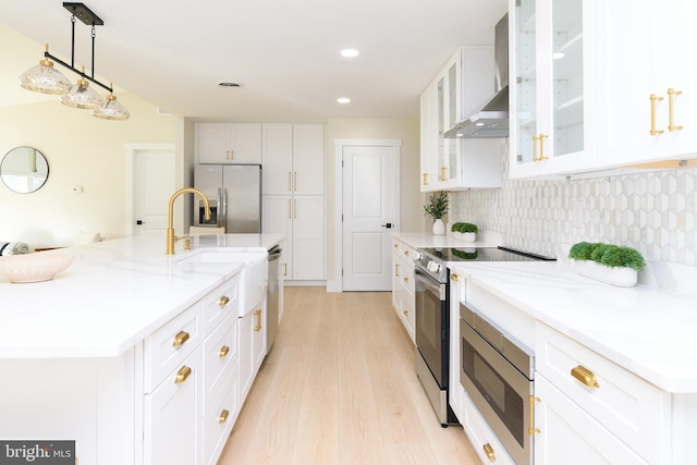 kitchen with stainless steel appliances, white cabinetry, decorative light fixtures, decorative backsplash, and light hardwood / wood-style floors