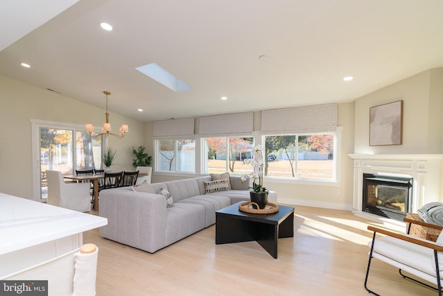 living room featuring an inviting chandelier, vaulted ceiling, and light hardwood / wood-style floors