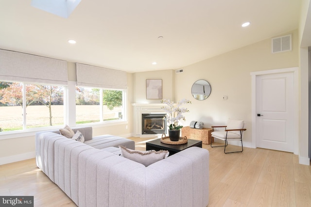 living room featuring light hardwood / wood-style floors and vaulted ceiling with skylight