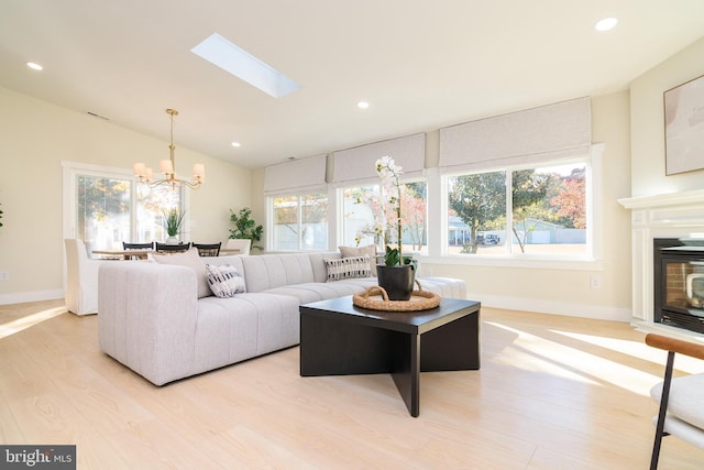 living room featuring light hardwood / wood-style flooring, a skylight, a chandelier, and plenty of natural light