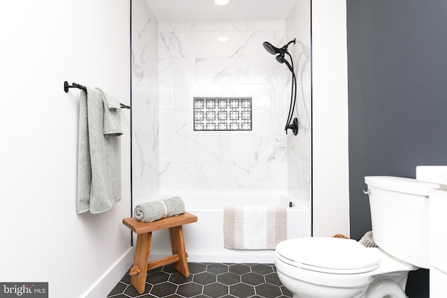 bathroom with toilet, tiled shower / bath, and tile patterned flooring