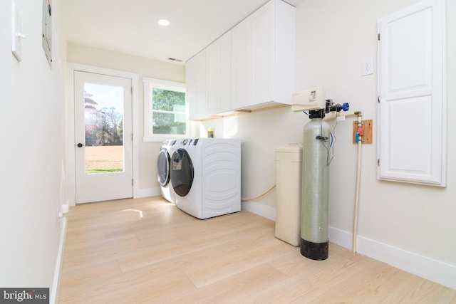 laundry room with cabinets, light hardwood / wood-style flooring, and washer and clothes dryer