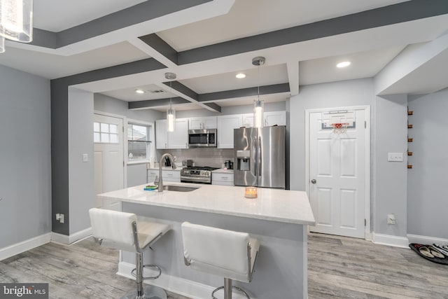 kitchen featuring light wood-type flooring, stainless steel appliances, white cabinetry, and hanging light fixtures