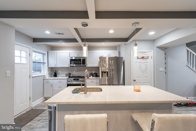 kitchen with a kitchen breakfast bar, hanging light fixtures, light stone countertops, appliances with stainless steel finishes, and white cabinetry