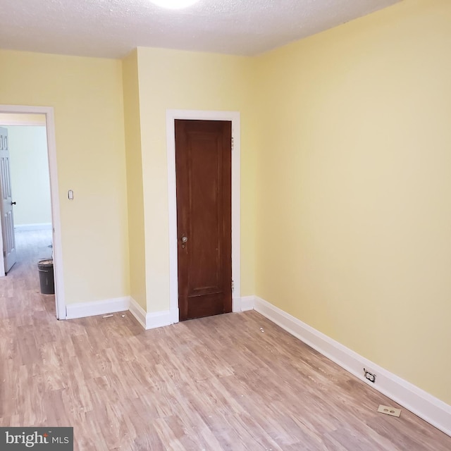 spare room with a textured ceiling and light hardwood / wood-style floors