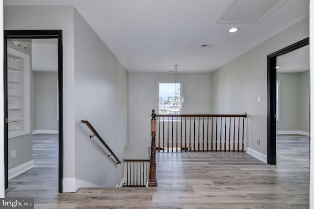 stairs featuring wood-type flooring and a notable chandelier