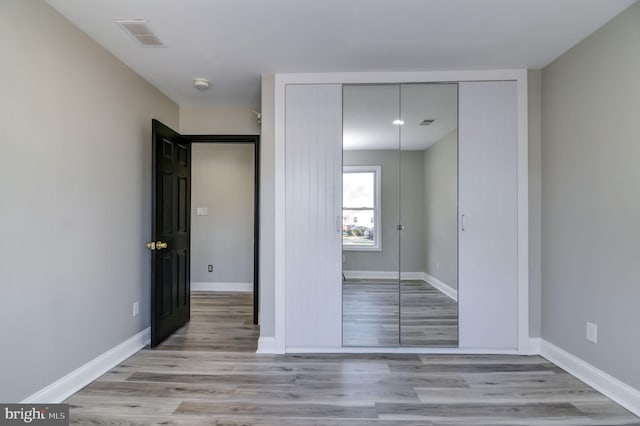 unfurnished bedroom featuring light hardwood / wood-style flooring and a closet