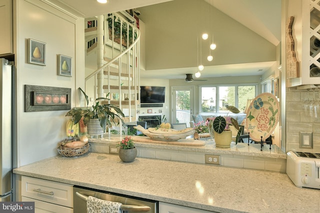 kitchen featuring backsplash, stainless steel refrigerator, high vaulted ceiling, light stone countertops, and ceiling fan