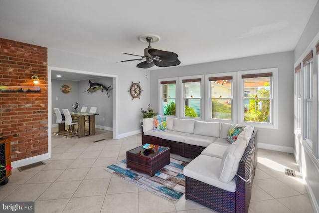 tiled living room featuring ceiling fan and brick wall