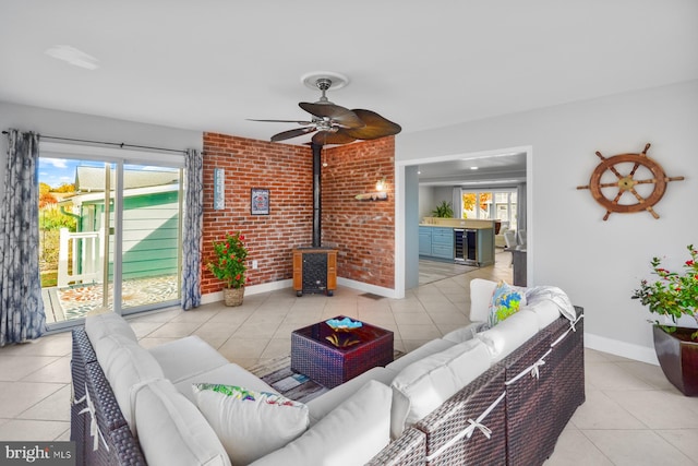 tiled living room featuring wine cooler, plenty of natural light, brick wall, and a wood stove