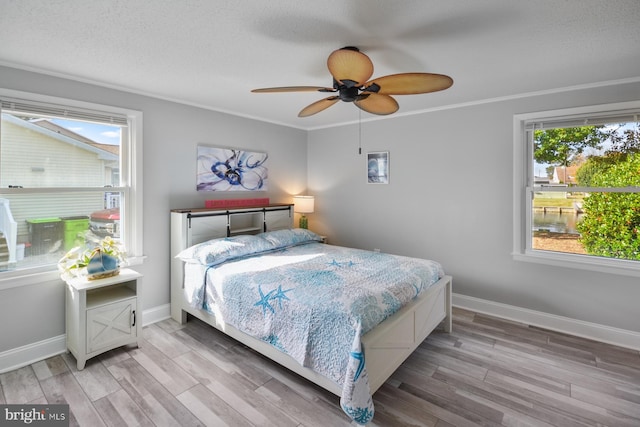 bedroom featuring crown molding, ceiling fan, light hardwood / wood-style floors, and a textured ceiling