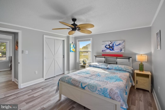 bedroom with multiple windows, crown molding, a textured ceiling, and light wood-type flooring