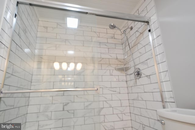 bathroom with a tile shower and toilet