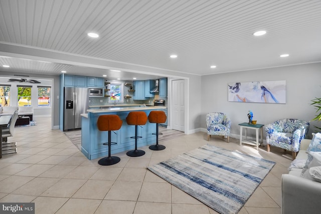 kitchen featuring light tile patterned floors, appliances with stainless steel finishes, a kitchen bar, tasteful backsplash, and blue cabinets