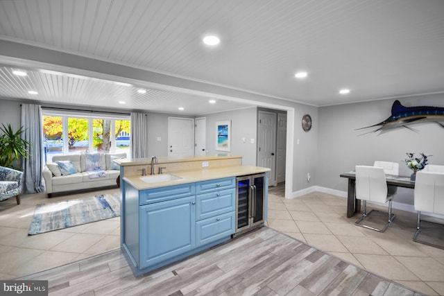 kitchen with sink, light hardwood / wood-style flooring, ornamental molding, blue cabinets, and beverage cooler