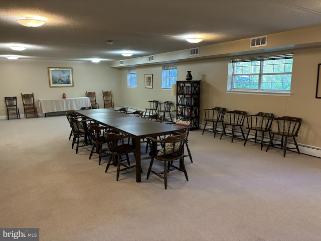 carpeted dining area featuring baseboard heating and a textured ceiling