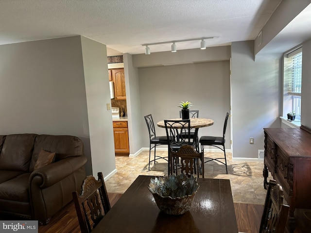 dining space featuring a textured ceiling and track lighting