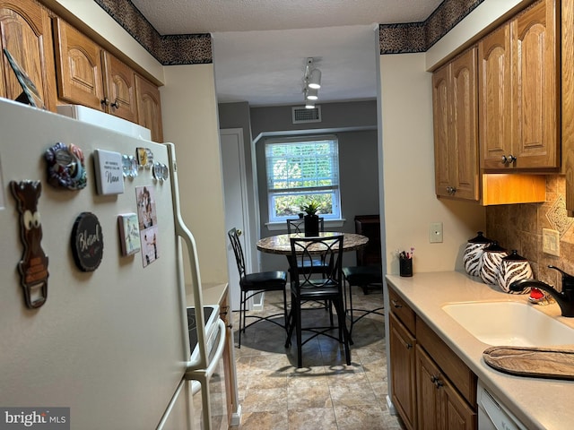 kitchen featuring tasteful backsplash, white fridge, range with electric stovetop, sink, and dishwashing machine