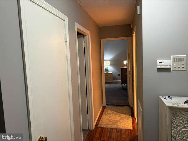 corridor featuring dark wood-type flooring and a textured ceiling