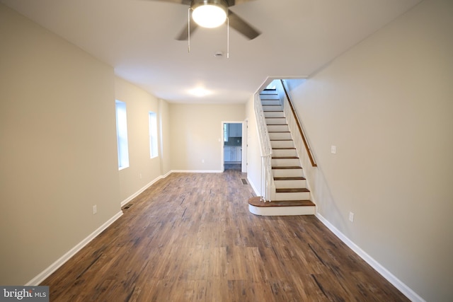 unfurnished living room featuring dark wood-type flooring and ceiling fan