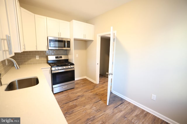 kitchen featuring white cabinets, hardwood / wood-style floors, sink, backsplash, and appliances with stainless steel finishes