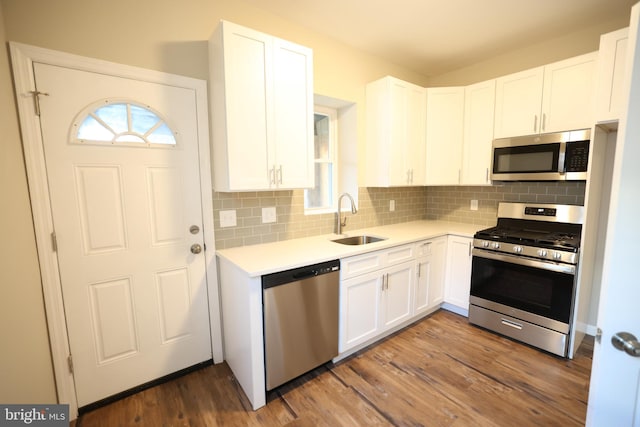 kitchen with stainless steel appliances, sink, tasteful backsplash, white cabinets, and dark wood-type flooring