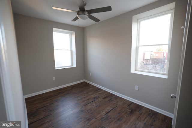 spare room featuring dark wood-type flooring, a wealth of natural light, and ceiling fan