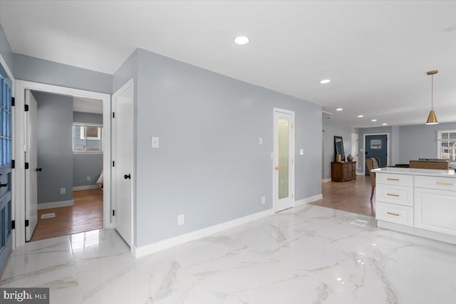 kitchen with white cabinets, decorative light fixtures, and light wood-type flooring