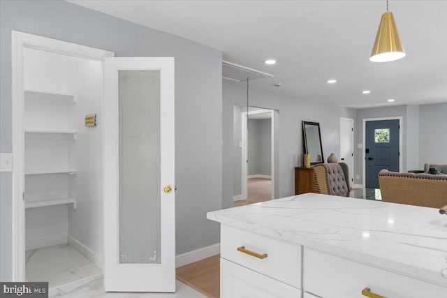 kitchen featuring light stone countertops, hanging light fixtures, and white cabinets