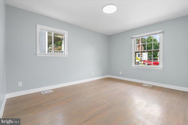 empty room with wood-type flooring and a healthy amount of sunlight