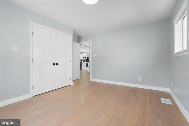 unfurnished bedroom with a closet and light wood-type flooring