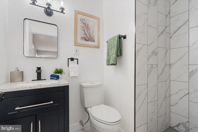 bathroom with toilet, vanity, and tiled shower