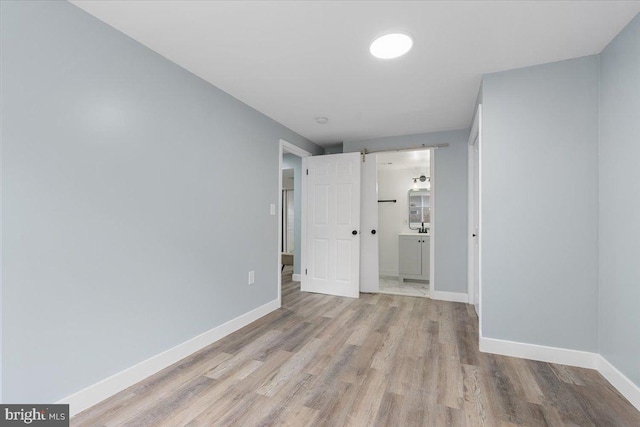 empty room with light wood-type flooring and a barn door