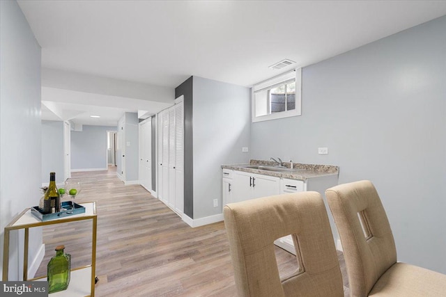 corridor with light hardwood / wood-style floors and sink