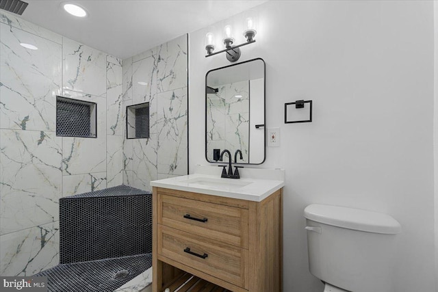 bathroom featuring tiled shower, toilet, and vanity