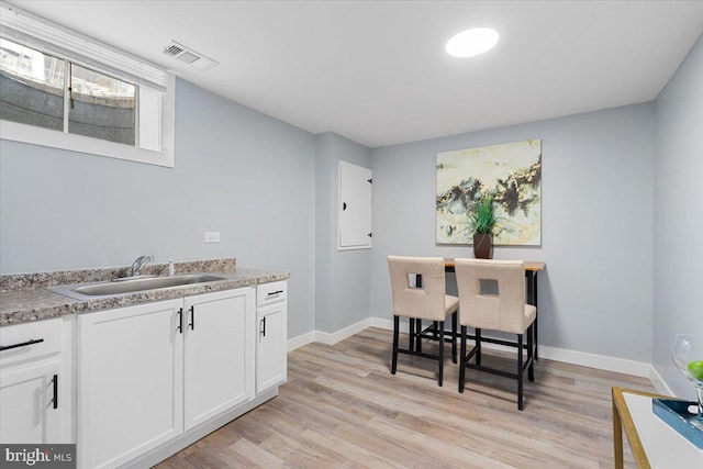 kitchen featuring white cabinetry, sink, and light wood-type flooring