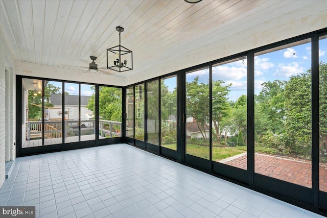 unfurnished sunroom with a healthy amount of sunlight, a chandelier, and wooden ceiling