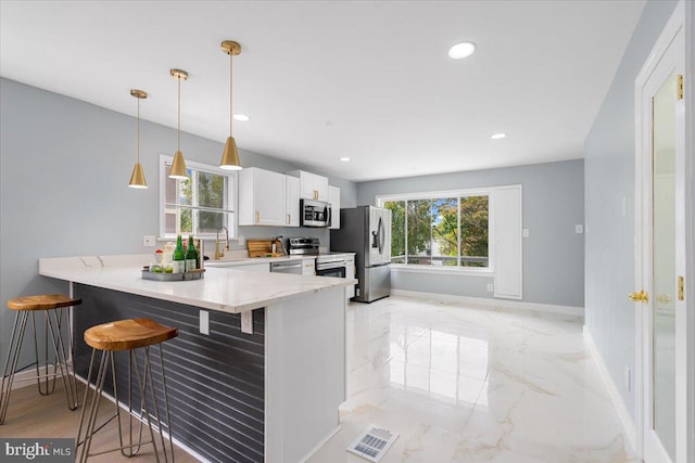 kitchen featuring kitchen peninsula, stainless steel appliances, a breakfast bar, and plenty of natural light