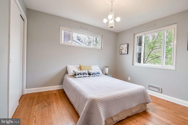 bedroom featuring a closet, light hardwood / wood-style flooring, and a notable chandelier