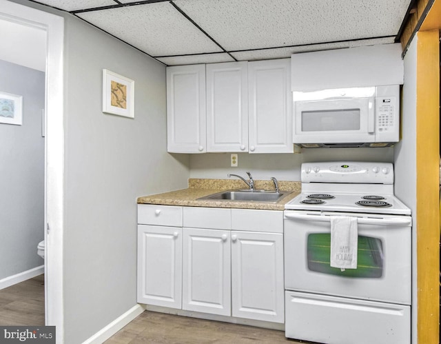 kitchen with a paneled ceiling, white appliances, sink, light hardwood / wood-style flooring, and white cabinetry