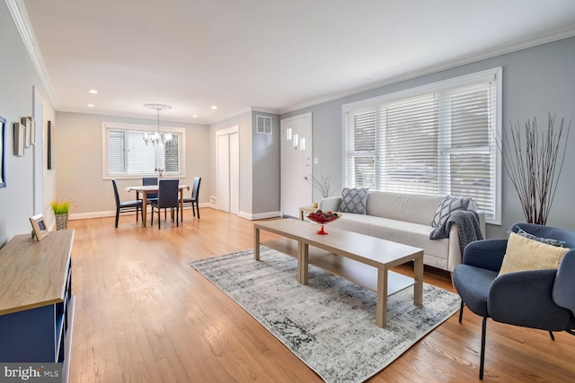 living room featuring light wood-type flooring, crown molding, and an inviting chandelier