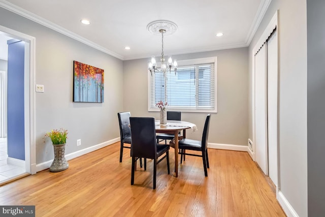 dining space with light hardwood / wood-style floors, crown molding, and an inviting chandelier