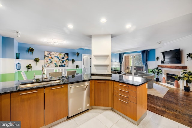 kitchen with stainless steel dishwasher, kitchen peninsula, dark stone counters, and sink