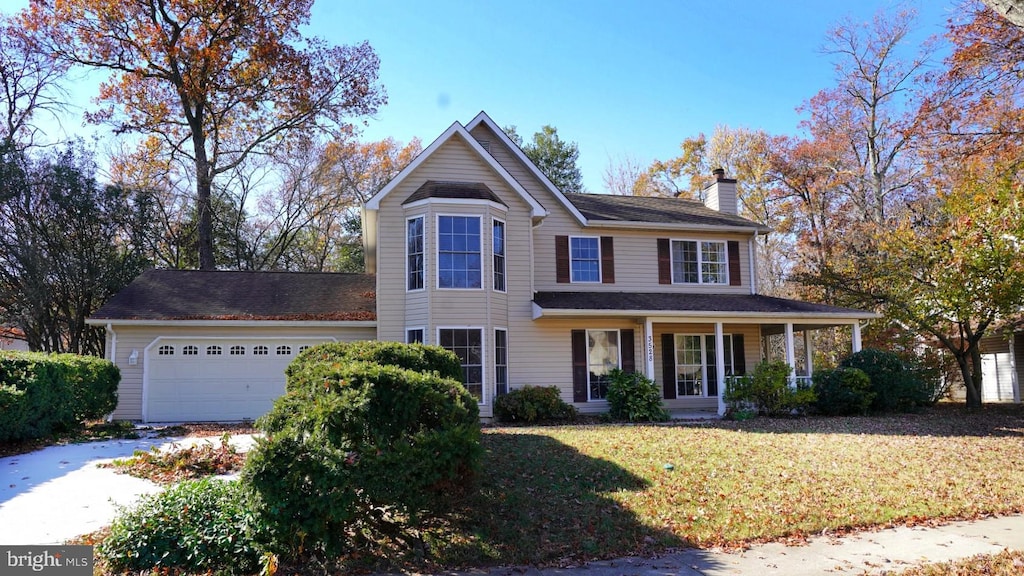 view of front of property with a porch, a garage, and a front lawn