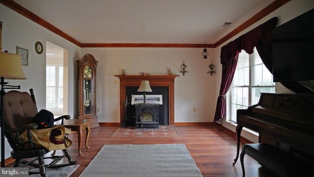 living area featuring a wood stove, light hardwood / wood-style flooring, a wealth of natural light, and crown molding