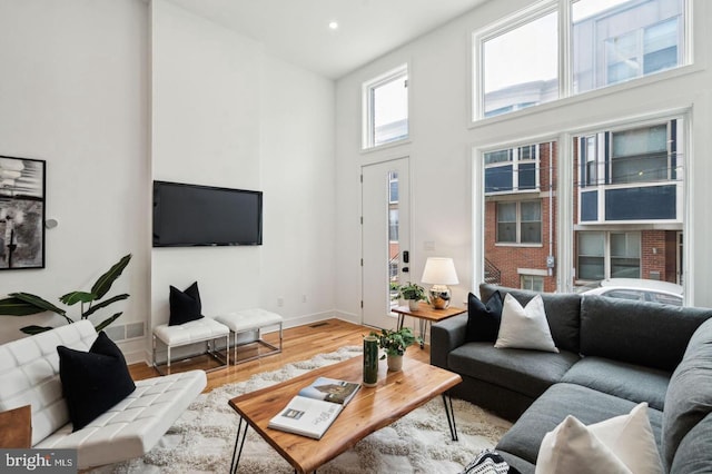 living room featuring a towering ceiling and wood-type flooring