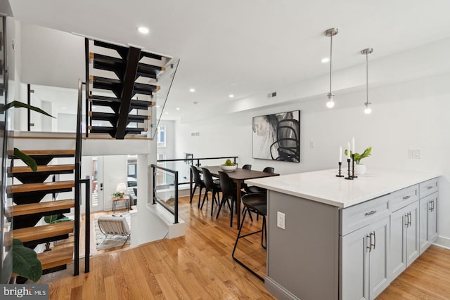 kitchen featuring pendant lighting, gray cabinets, a breakfast bar area, and light hardwood / wood-style flooring